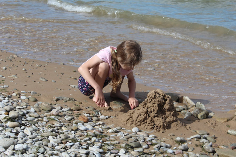 Kind spielt am Kiesstrand am Meer
