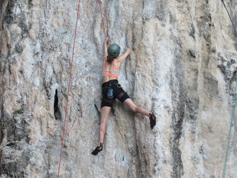 Kletterin an Kalksteinwand mit Seil