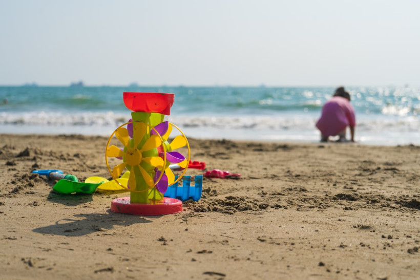 Kind spielt mit Sandspielzeug am Strand