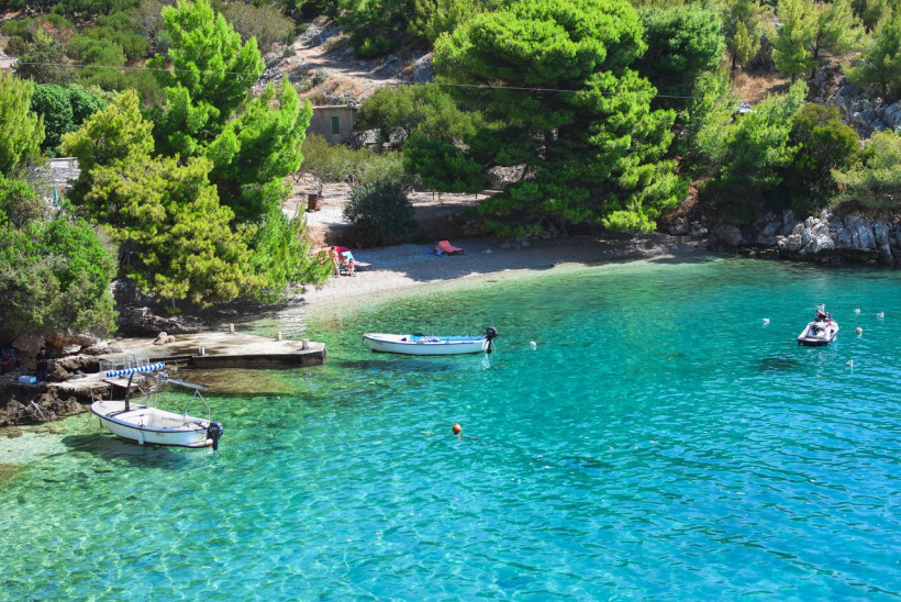 Versteckte Bucht mit Pinien, Booten und türkisblauem Wasser