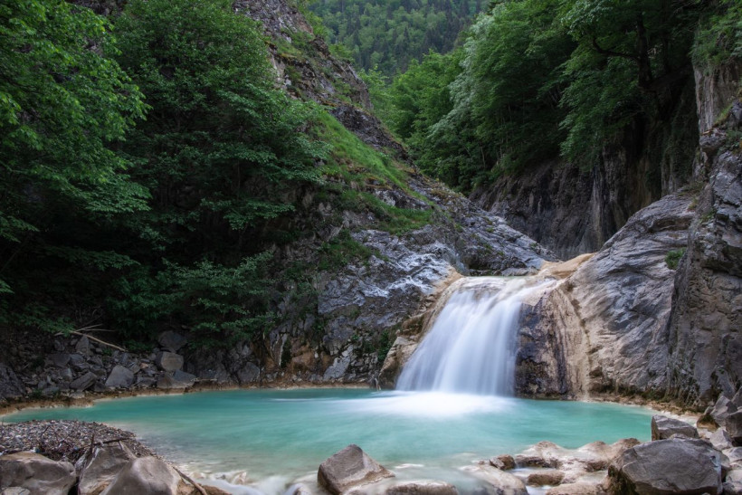 Wasserfall stürzt in türkisen Waldsee